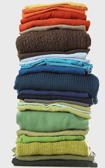 stacked clothes, laundry organization, clean clothing pile, assorted sweaters, home textile storage, folded garments, wardrobe essentials